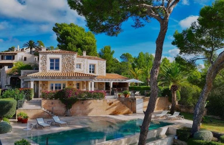 Stone finca framed by Mediterranean pines and gardens